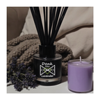 Black diffuser with lavender flowers and a purple candle on a neutral background