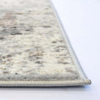 Close-up of a textured area rug corner showing a cream and gray marbled pattern with a light gray twisted border on a white surface.