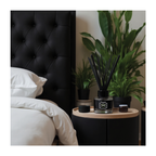 A black diffuser on a nightstand next to a bed with white bedding and a black headboard.