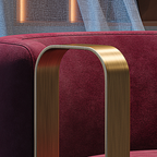 Close-up of a red upholstered chair with a gold metal armrest.