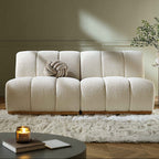 Beige sofa in a living room setting with a candle and plant on a table.