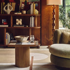 Living room with wooden bookshelf, table, and armchair.
