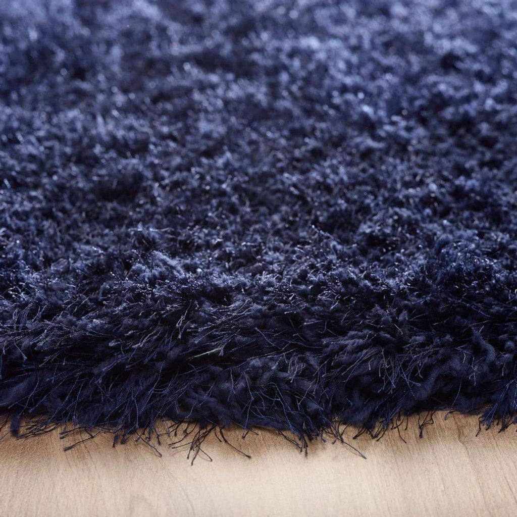 Close-up of a dark blue shaggy rug on a wooden floor