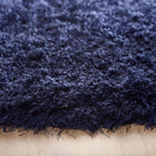Close-up of a dark blue shaggy rug on a wooden floor
