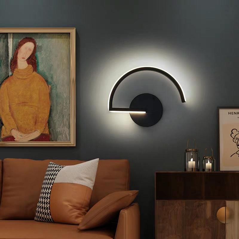 Modern wall lamp in a living room setting with a brown sofa and framed artwork.
