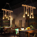 Rustic wooden pendant lights hanging in a dimly lit room with tables and chairs.
