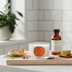 Candle with an orange label and a bottle on a wooden tray against a tiled wall.