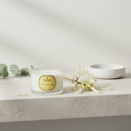 Parks candle on a white surface with flowers and a bowl in the background