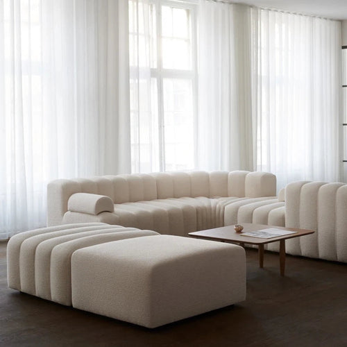 Beige sectional sofa in a modern living room with large windows.