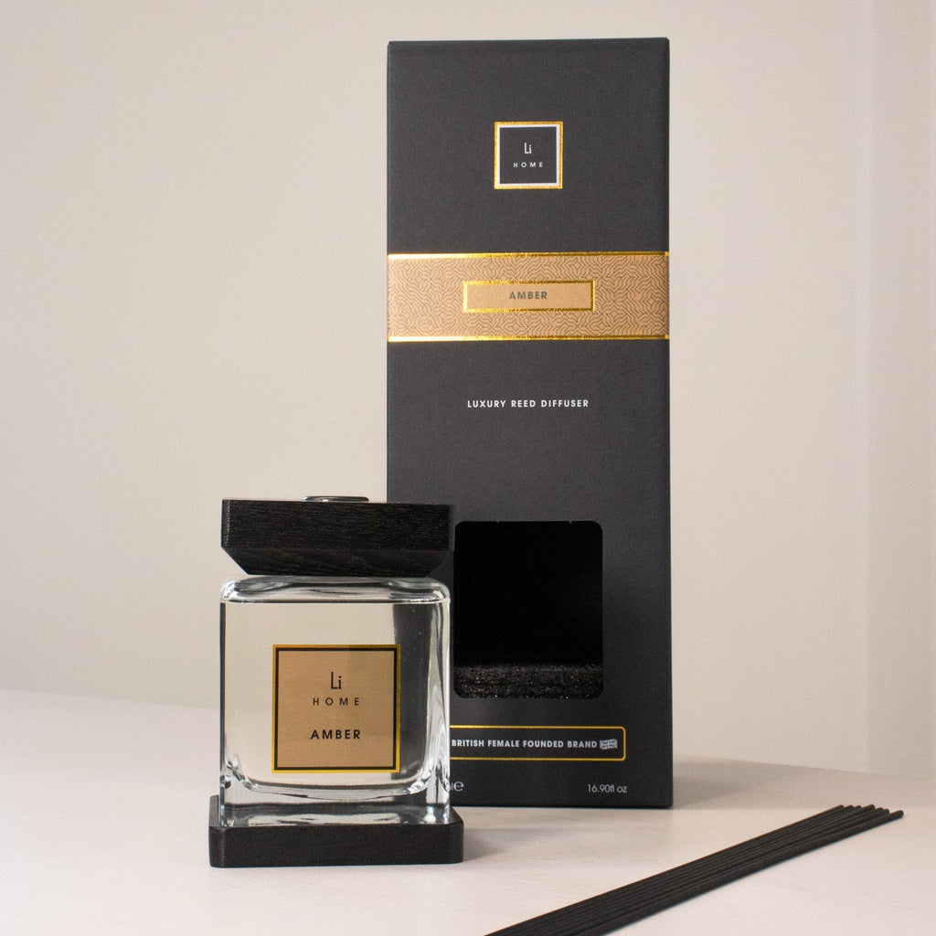 Candle and packaging with gold accents on a neutral background