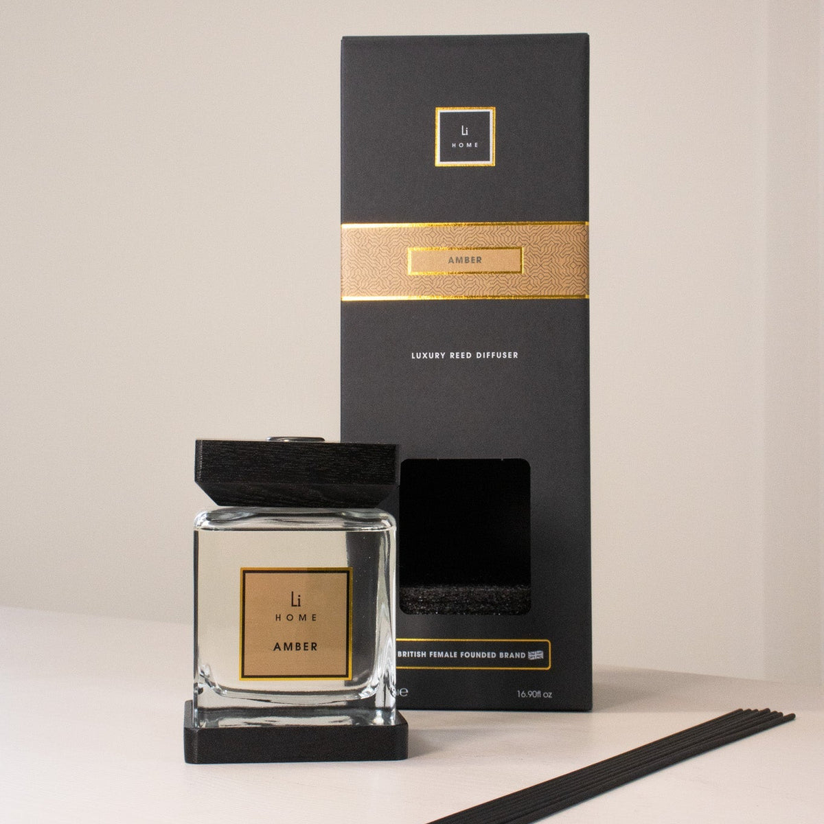 Candle and packaging with gold accents on a neutral background