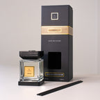 A black and gold scented candle with packaging on a white background