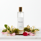 Bottle of 'Blossom' product with flowers and petals on a white background