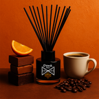 Diffuser with reeds, orange slice, chocolate bars, coffee cup, and coffee beans on an orange background