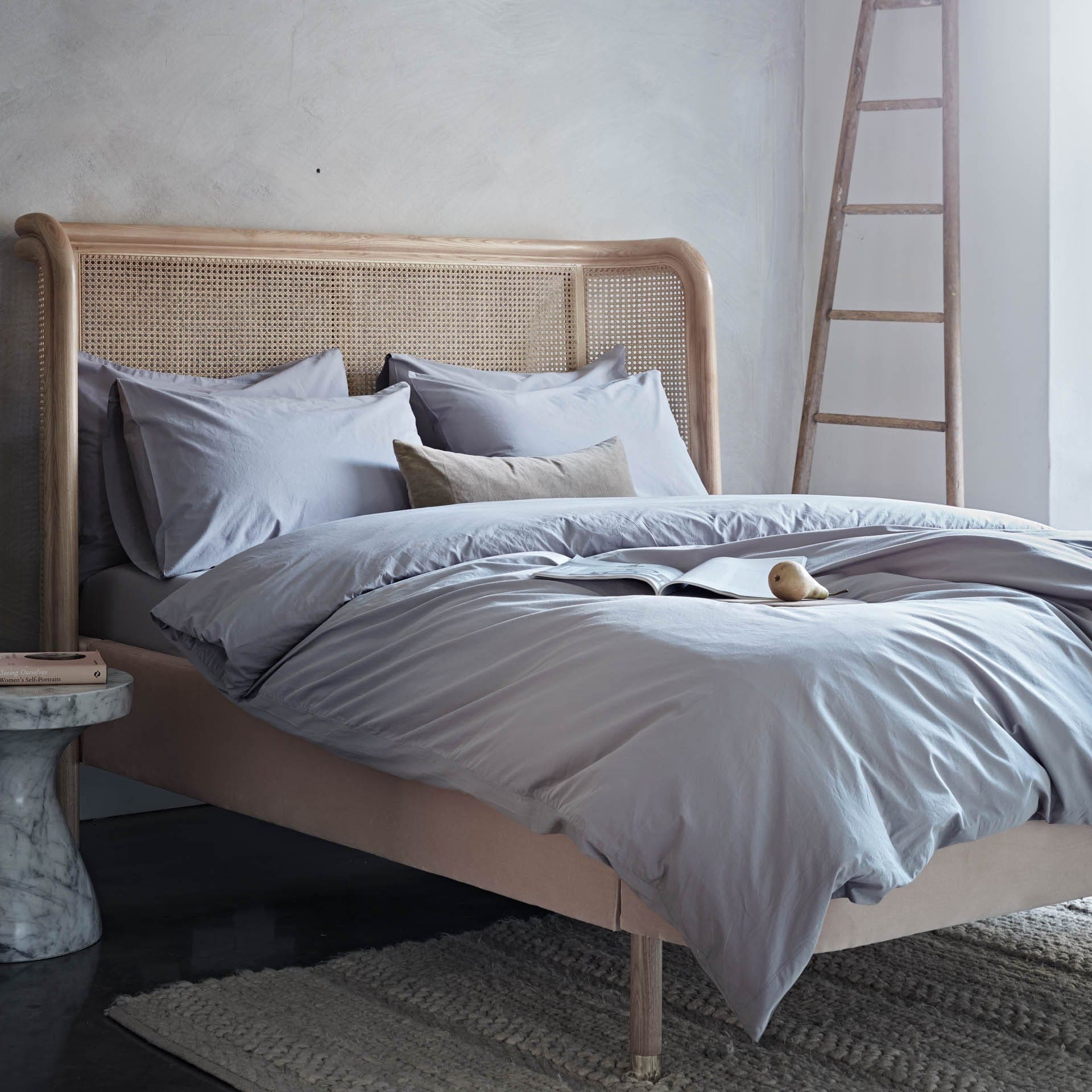 Bedroom with a bed featuring light gray bedding and a wooden headboard.