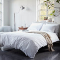 Neatly made bed with white bedding in a bright bedroom.