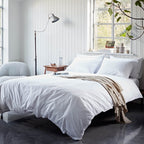 Neatly made bed with white bedding in a bright bedroom.