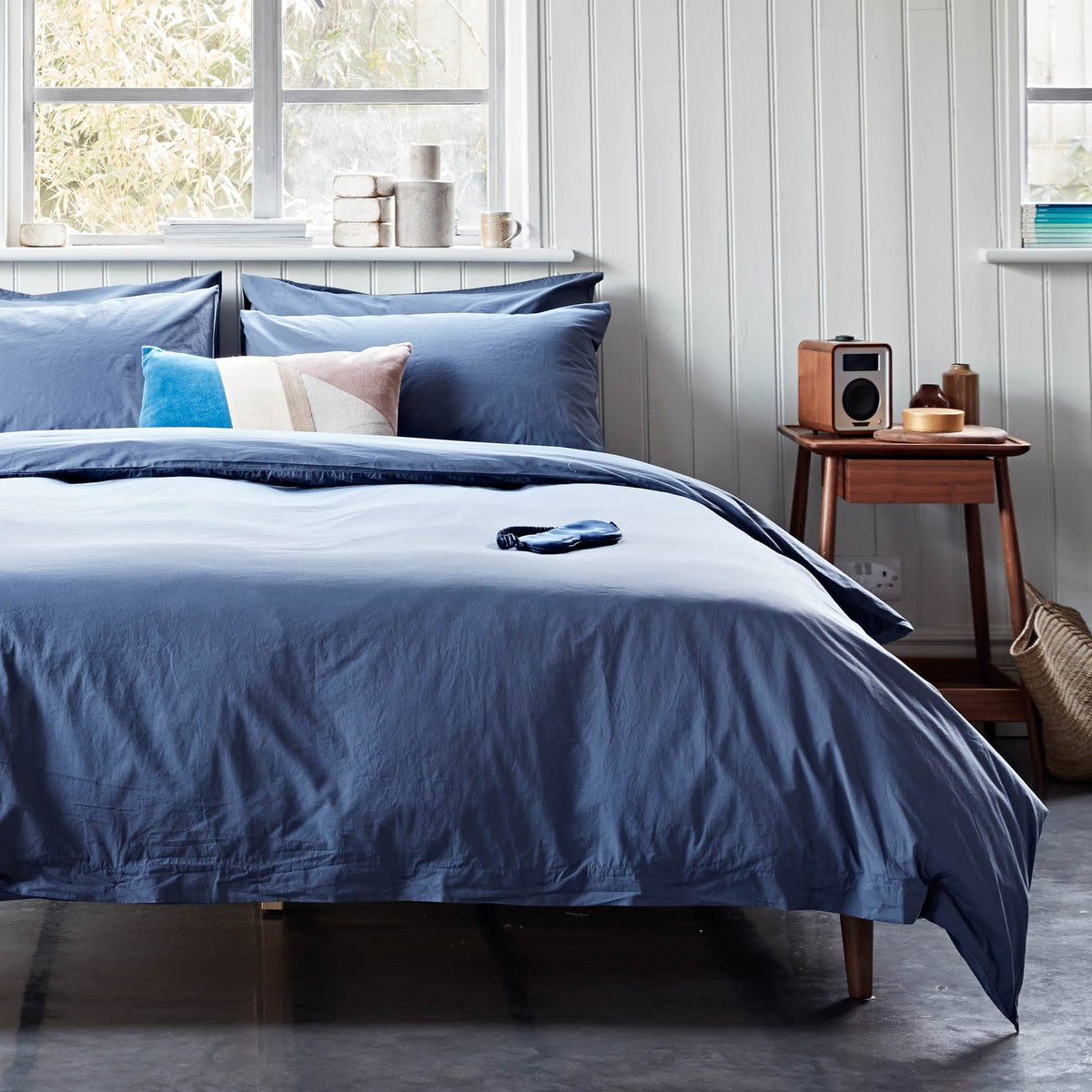Bedroom with blue bedding and a wooden nightstand.