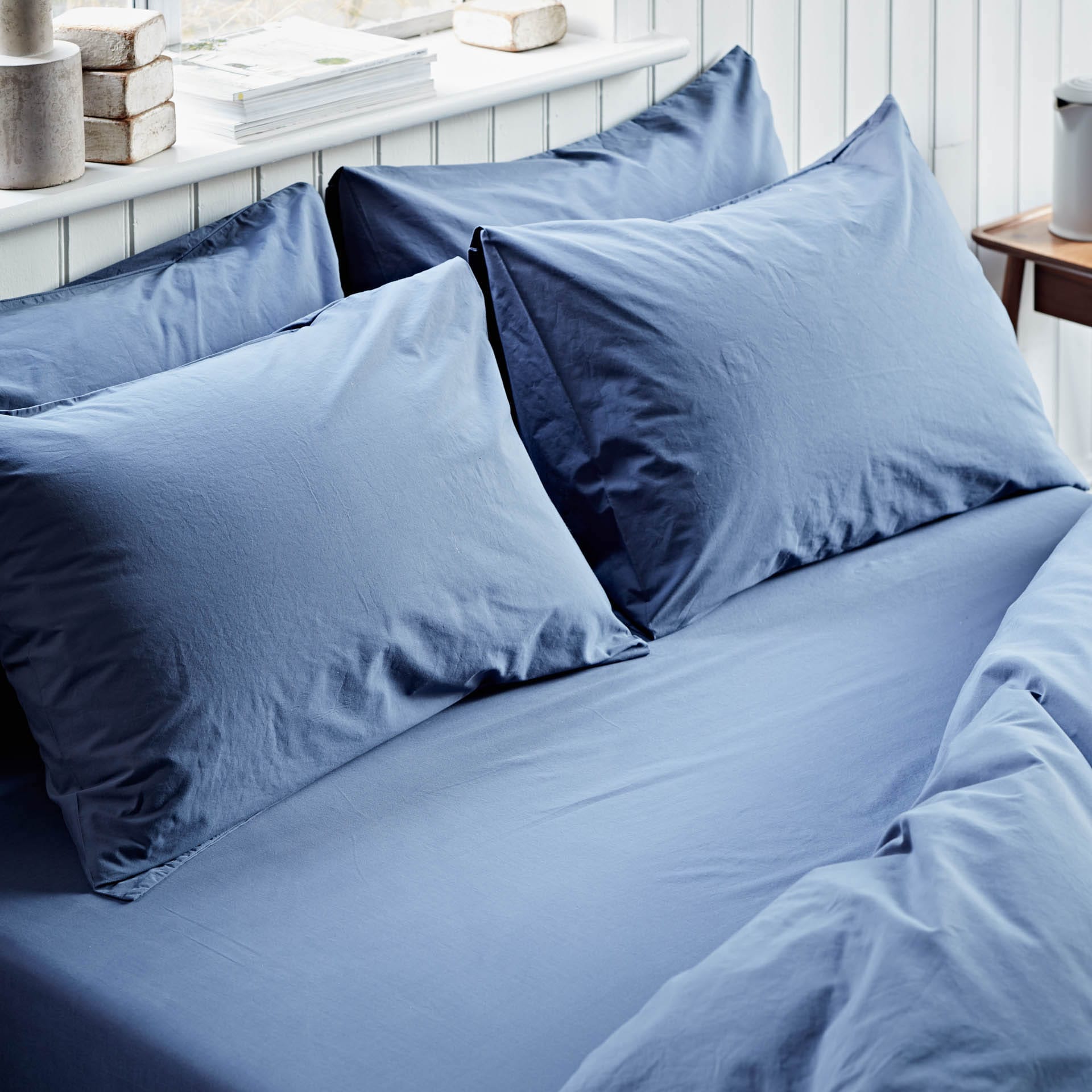 Blue bedding set with pillows on a bed in a bedroom setting.