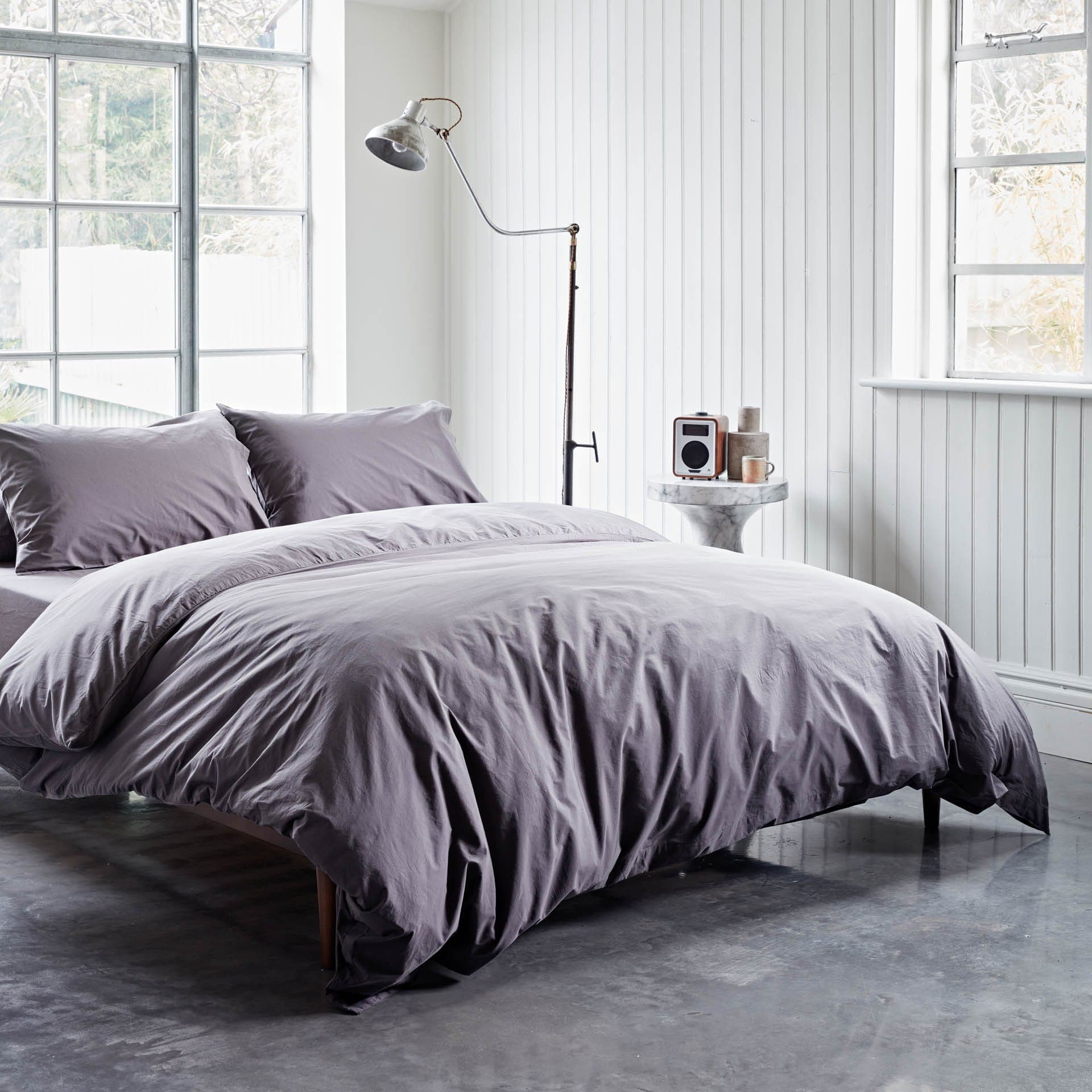 Bedroom with gray bedding and a lamp in a bright room