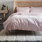 Bed with pink bedding and wicker headboard in a bedroom setting