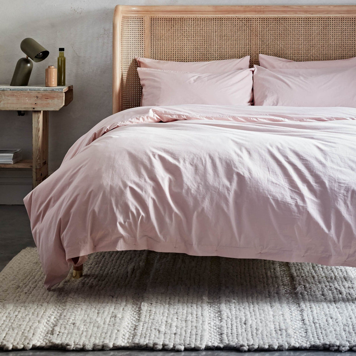 Bed with pink bedding and wicker headboard in a bedroom setting