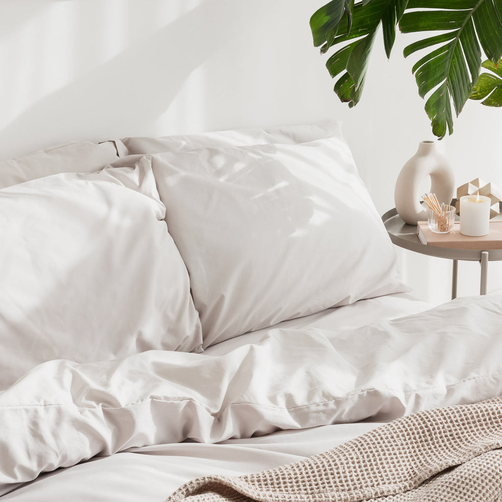 Neatly made bed with white bedding and a side table with decor items.