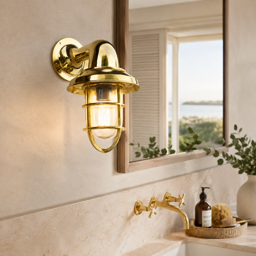 Gold wall-mounted light fixture in a bathroom setting with a mirror and window.