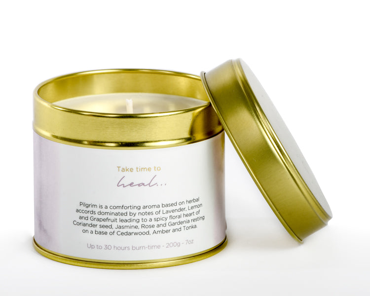 Candle in a gold lid container with a white label on a white background