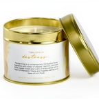 Candle in a gold and white tin with a label on a white background
