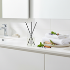 Bathroom counter with towels, diffuser, and decorative items on a white tiled wall background