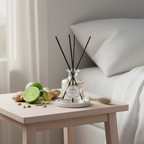 Diffuser with reeds on a table next to limes and ginger, with a neutral background