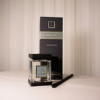 Home fragrance diffuser set with black packaging and clear diffuser on a neutral background