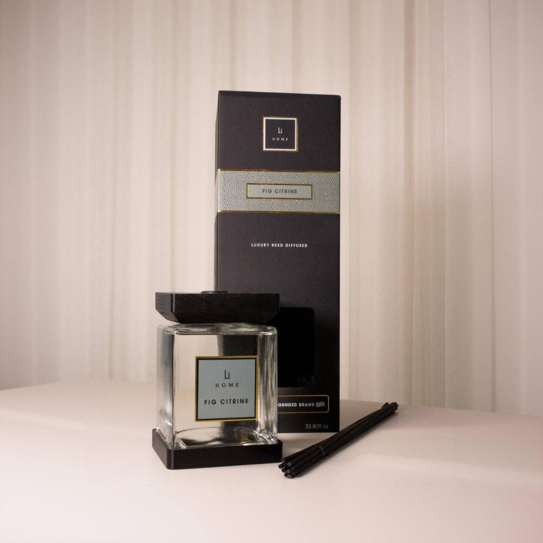 Home fragrance diffuser set with black packaging and clear diffuser on a neutral background