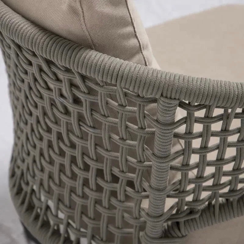 Close-up of a woven chair with beige cushion on a light background