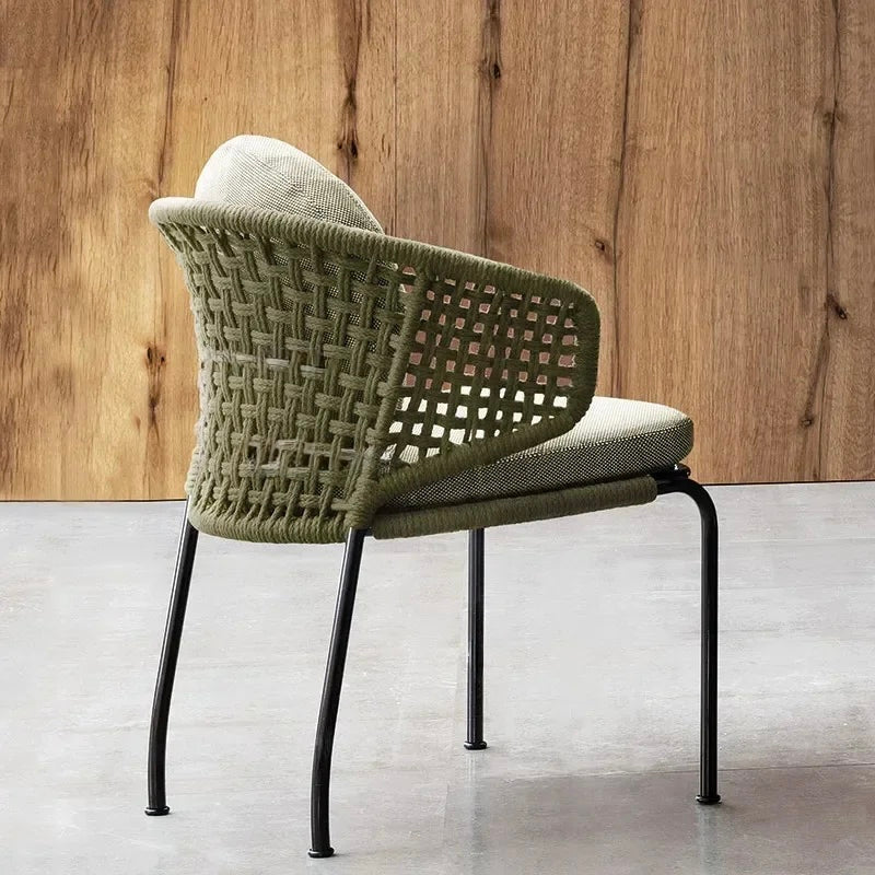 Modern chair with woven backrest and cushioned seat against a wooden wall.