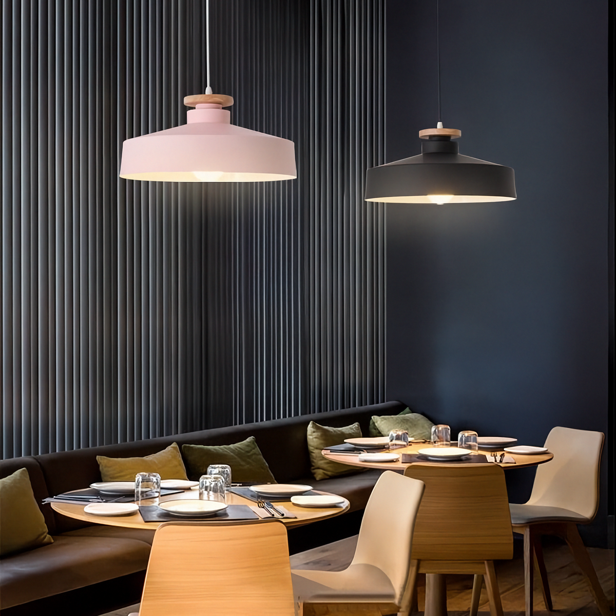 Modern restaurant interior with pendant lights, tables, and chairs against a dark wall.