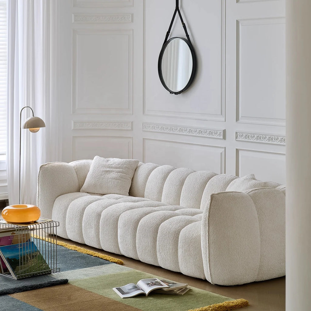 Beige sofa in a stylish living room with decorative wall paneling and a round mirror.