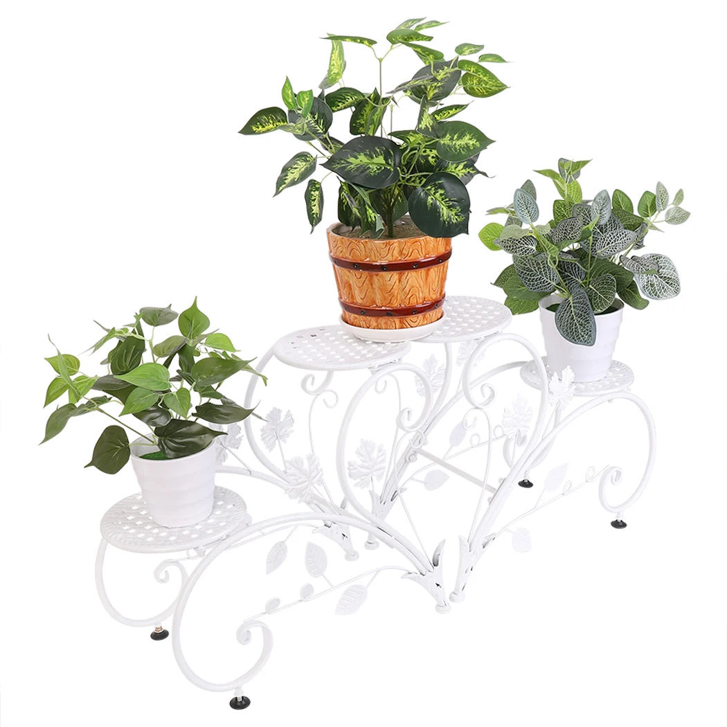 White decorative plant stand with three potted plants on a white background