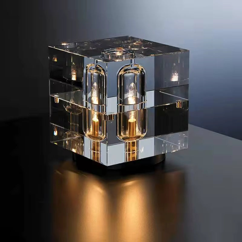 Modern glass cube table lamp with multiple light bulbs on a dark surface.
