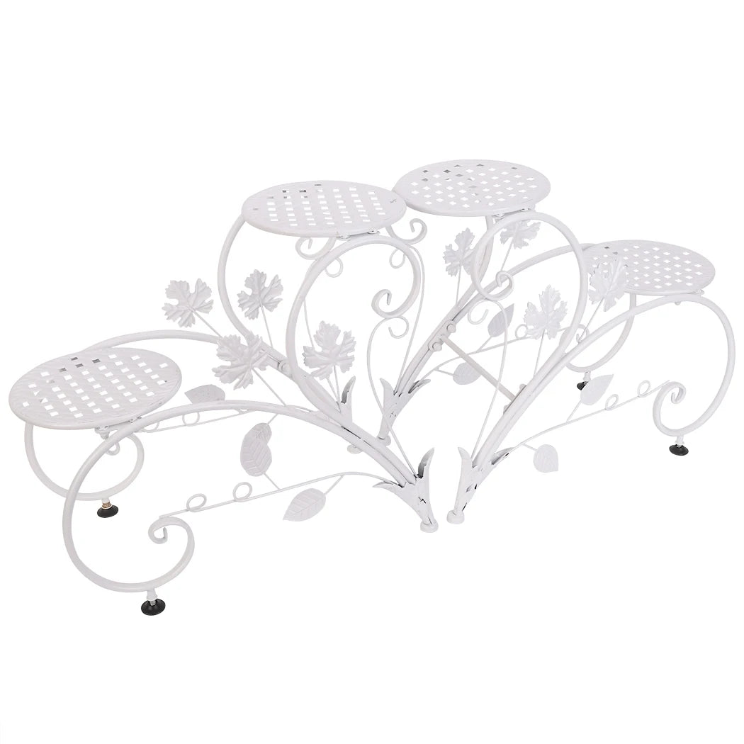 White metal decorative plant stand with floral designs on a white background