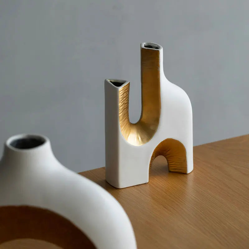 Two unique ceramic vases on a wooden surface with a plain background