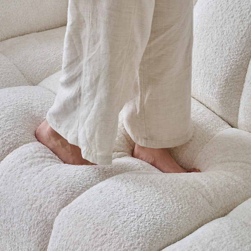 Person wearing white pants standing on a textured white surface