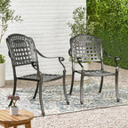 Two metal chairs on a patio with plants and a small table.