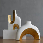 Two modern ceramic vases with gold accents on a dark gray background
