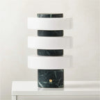 Modern table lamp with marble base and cylindrical design on a white surface.