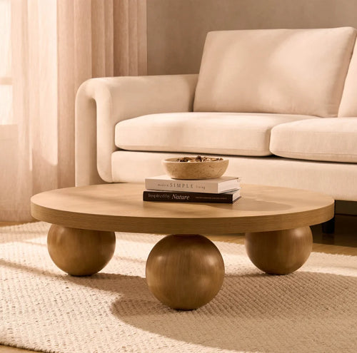 Wooden coffee table with books and a bowl on top, placed in front of a beige sofa.