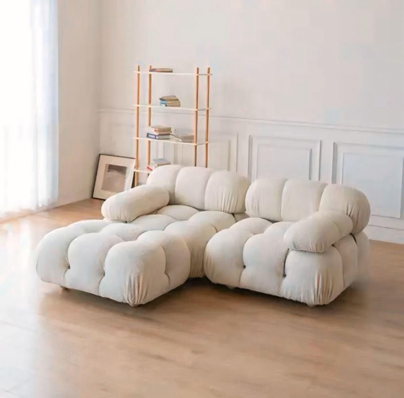 Beige sectional sofa in a room with a bookshelf and framed picture.