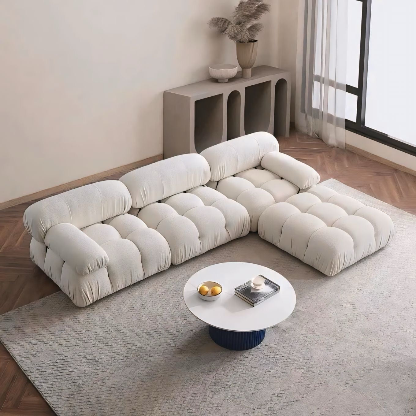 Modern living room with a beige sectional sofa, round coffee table, and decorative elements.