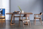 Dining table set with chairs in a room with a gray wall and wooden floor.